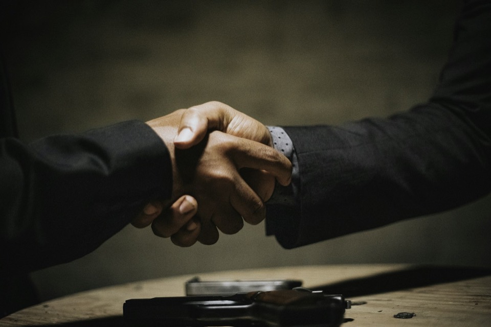 Dos personas estrechándose la mano sobre una mesa al cerrar un trato