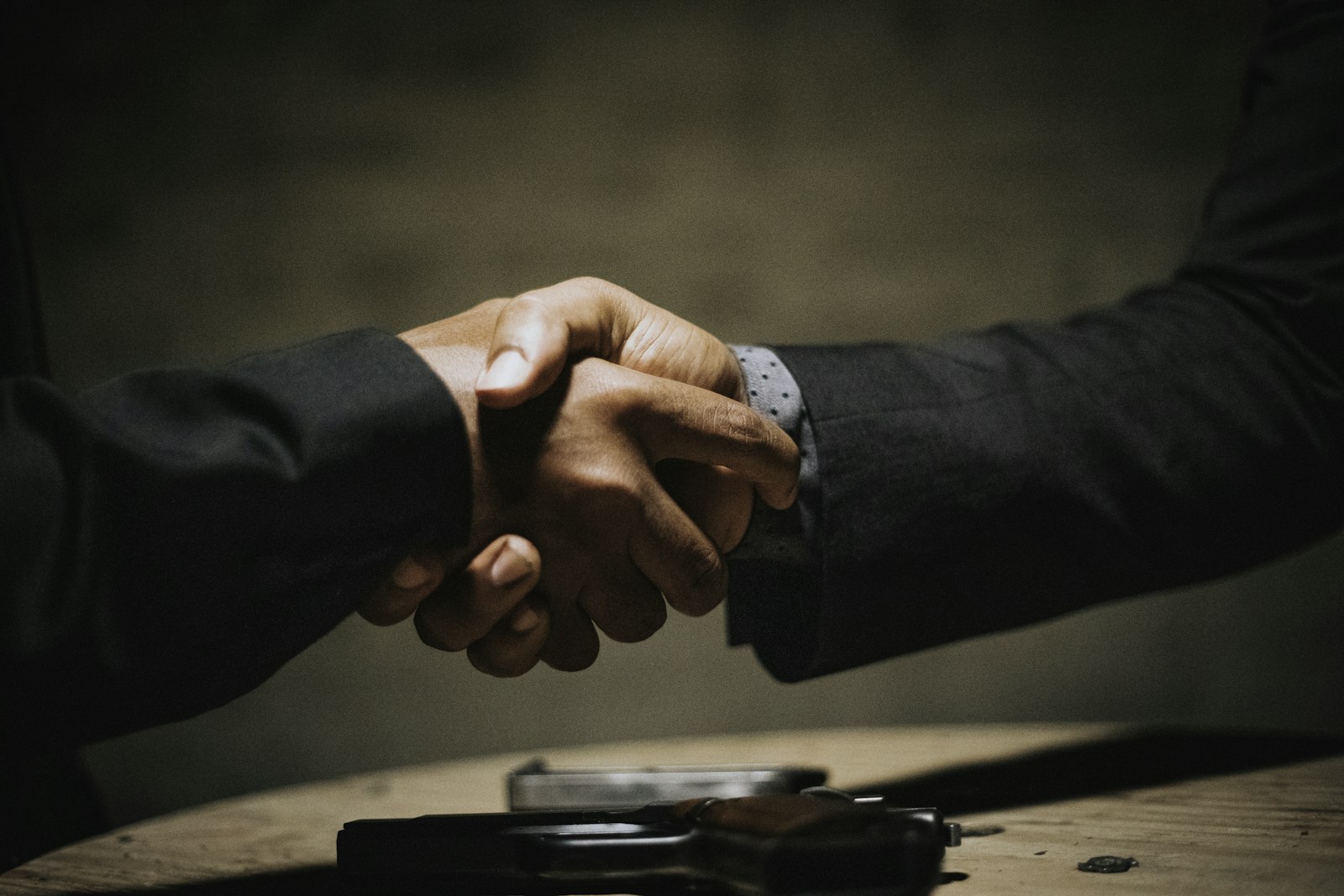 Dos personas estrechándose la mano sobre una mesa al cerrar un trato