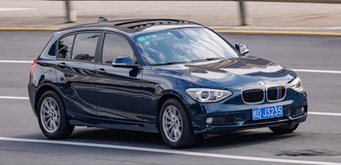 BMW Serie 1 F20 azul oscuro de tres cuartos delantero circulando por una carretera