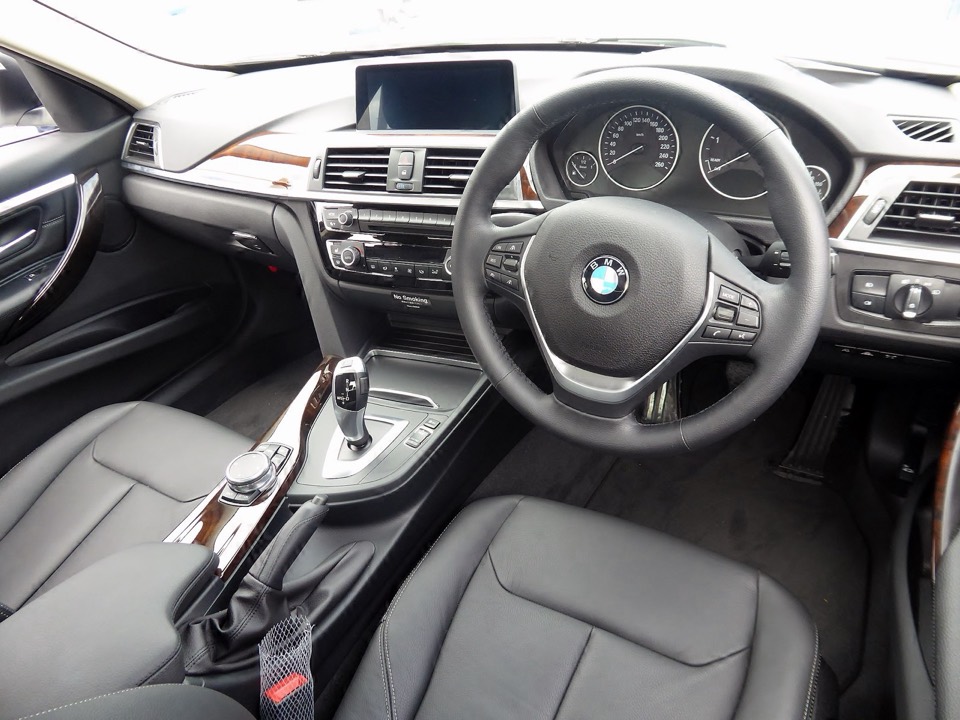 Puesto de conducción de un BMW Serie 3 F30: volante, cuadro de instrumentos analógico y pantalla central