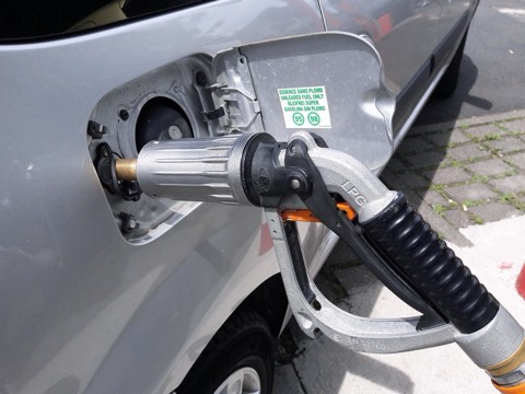 Boquerel de autogás GLP acoplado a la boca de llenado de un coche, junto a la pegatina de gasolina sin plomo