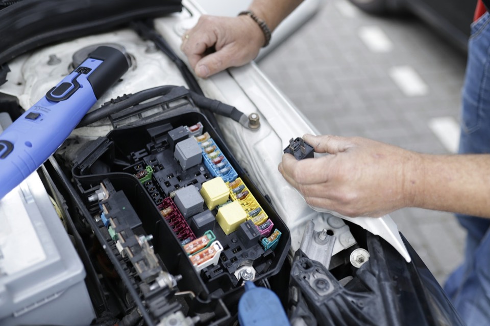 Manos revisando la caja de fusibles de un coche