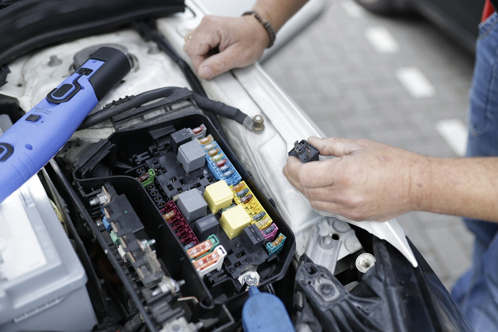 Manos revisando la caja de fusibles de un coche