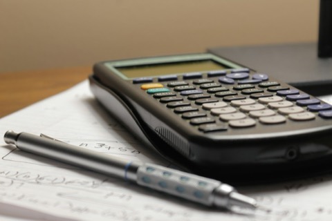Calculadora y bolígrafo sobre un papel con cuentas escritas a mano