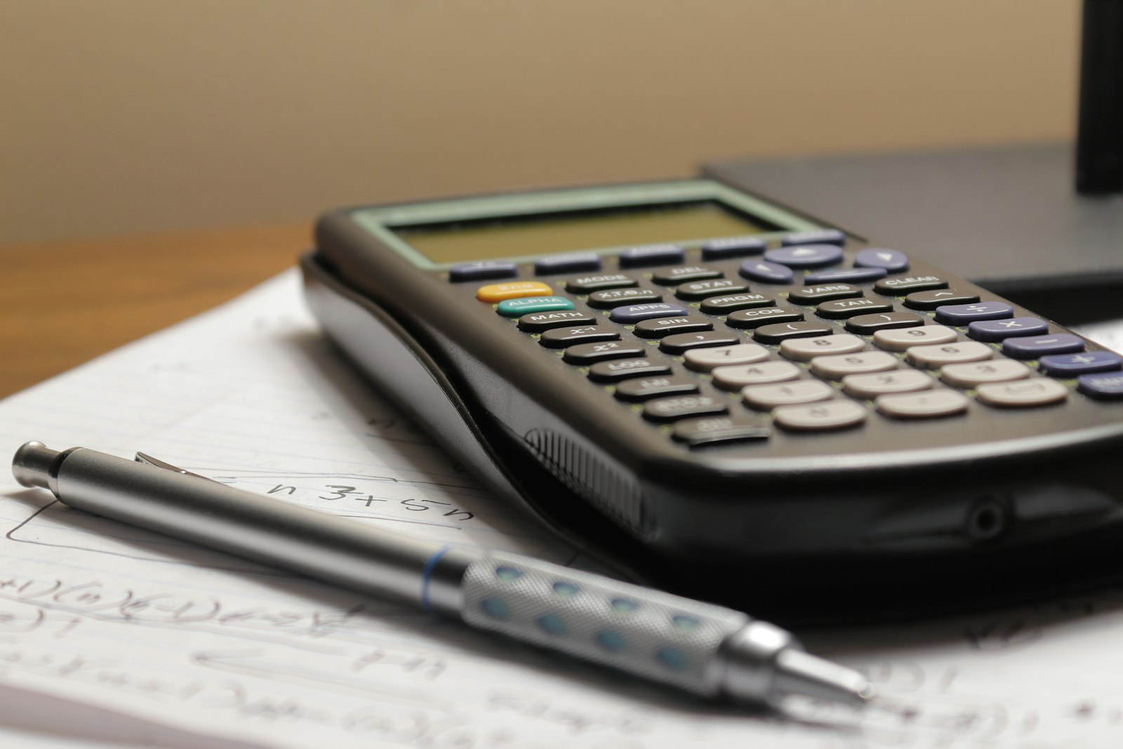 Calculadora y bolígrafo sobre un papel con cuentas escritas a mano