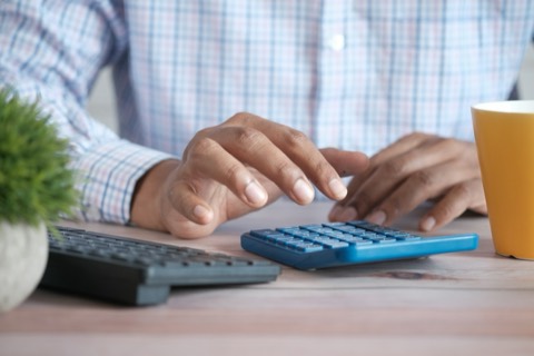 Manos usando una calculadora sobre un escritorio con papeles