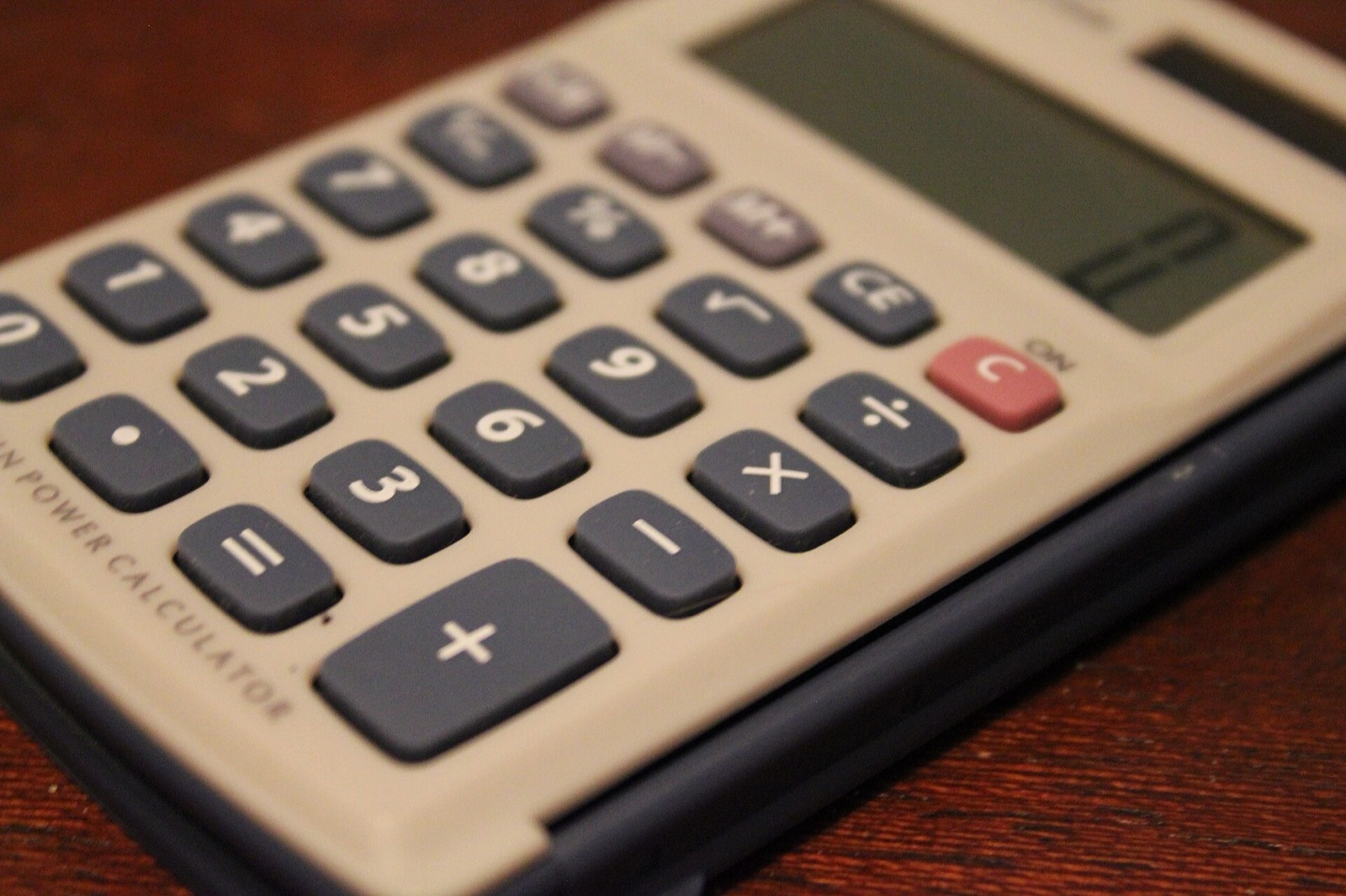 Primer plano del teclado de una calculadora de bolsillo sobre una mesa de madera
