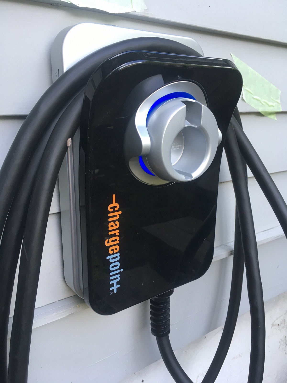 Cargador de coche eléctrico montado en la pared exterior de una vivienda, con el cable recogido