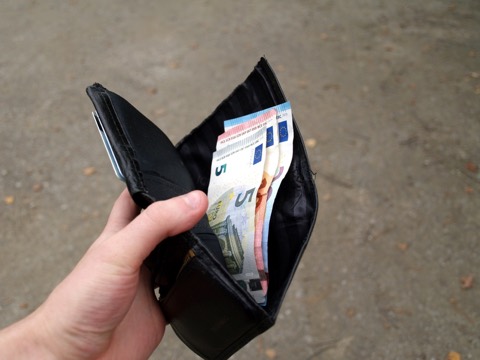 Mano sosteniendo una cartera abierta con varios billetes de euro de pequeño valor