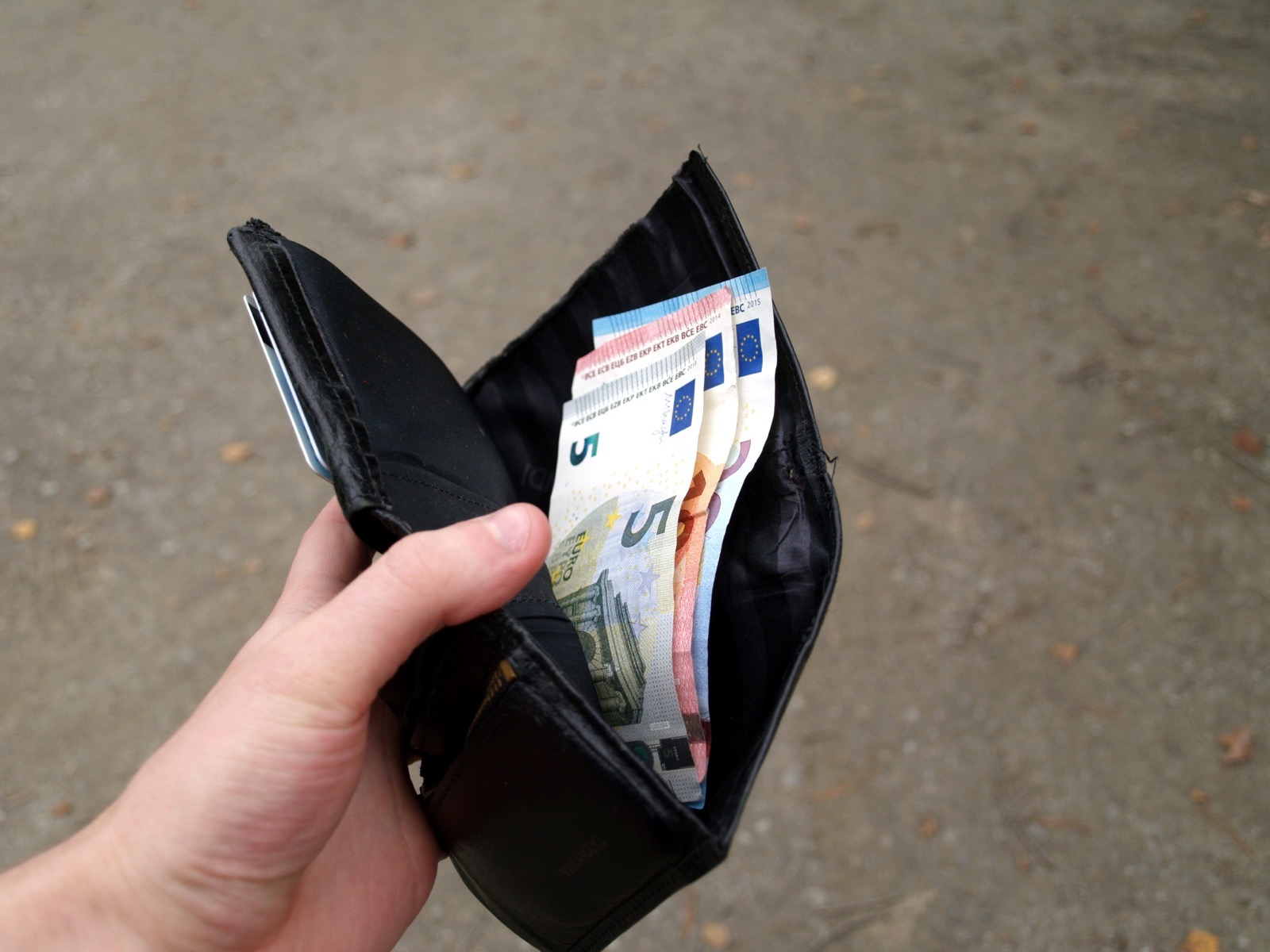 Mano sosteniendo una cartera abierta con varios billetes de euro de pequeño valor