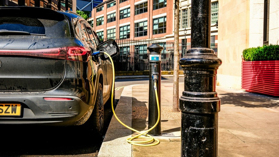 Coche eléctrico enchufado a un poste de recarga en la calle de una ciudad