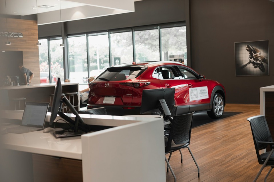 Sala de exposición de un concesionario con un coche y el mostrador