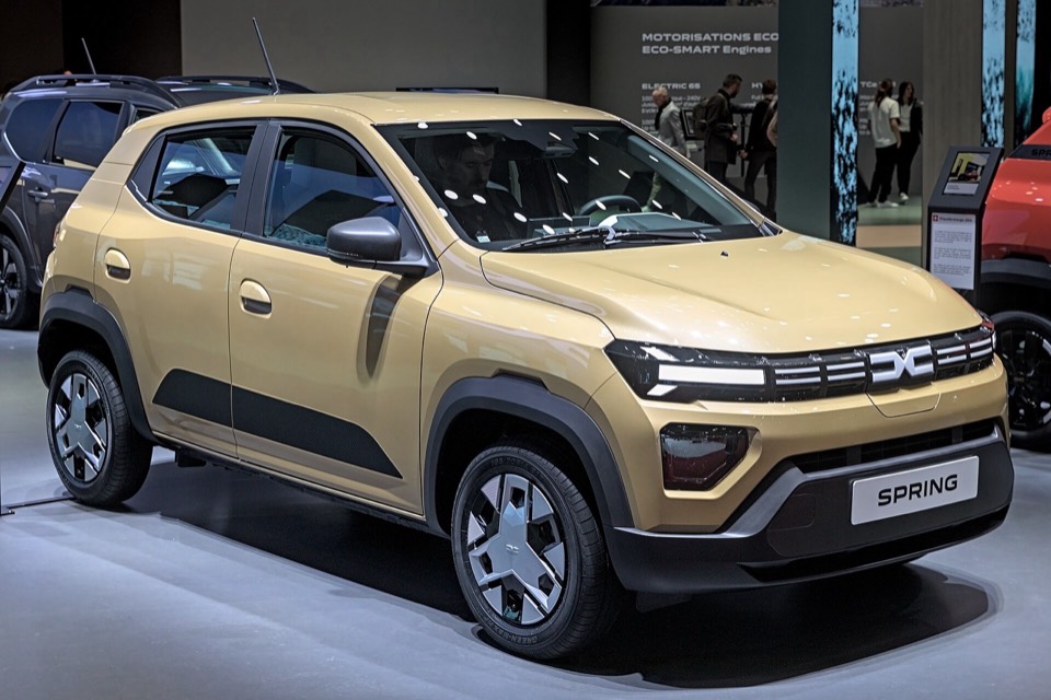 Dacia Spring eléctrico beige de tres cuartos delantero en un salón del automóvil