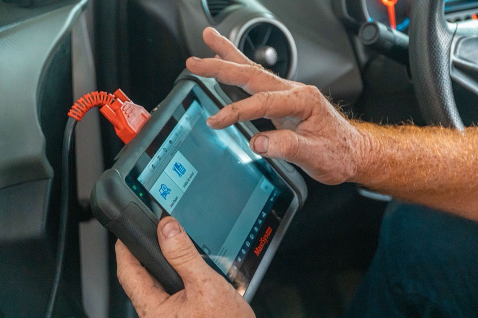 Equipo de diagnóstico conectado al puerto OBD de un coche, con la lectura en una tableta