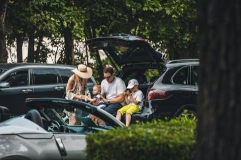 Varias personas sentadas en el maletero abierto de un coche
