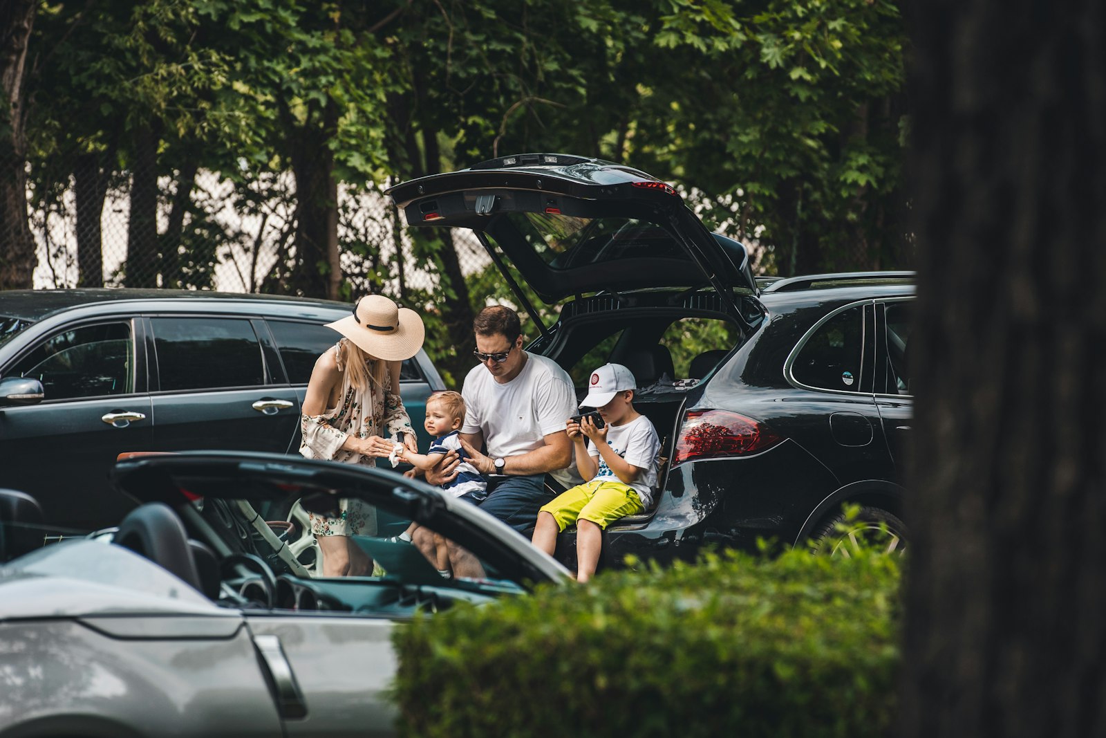 Varias personas sentadas en el maletero abierto de un coche