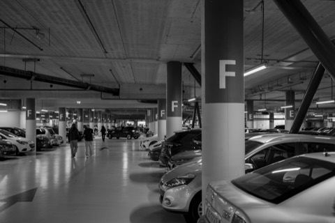 Coches aparcados muy juntos en un garaje subterráneo, junto a un pilar señalizado