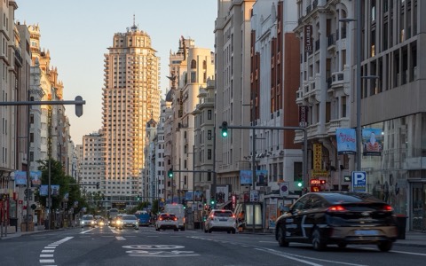 Tráfico circulando por la Gran Vía de Madrid al atardecer, con el Edificio España al fondo