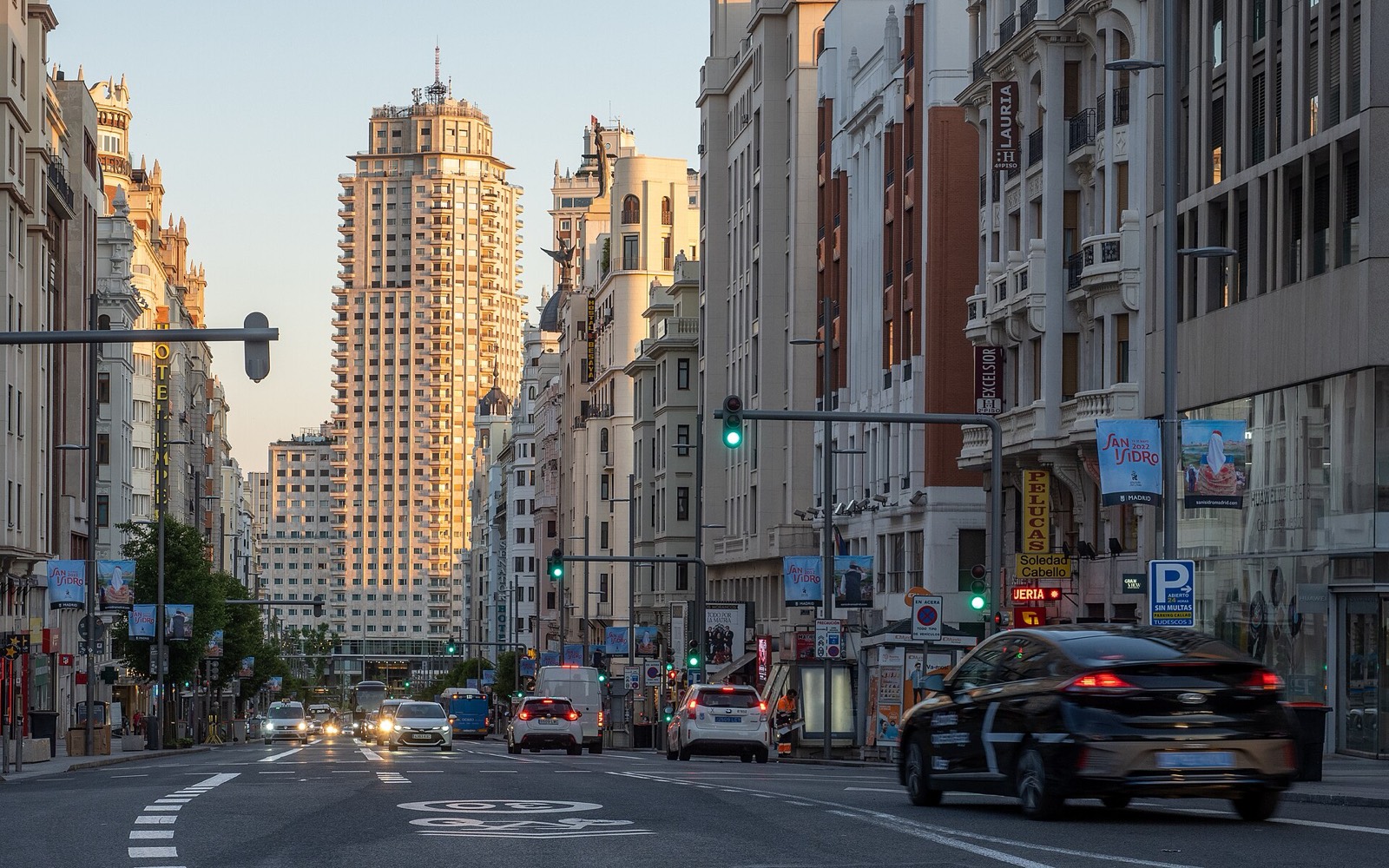 Tráfico circulando por la Gran Vía de Madrid al atardecer, con el Edificio España al fondo