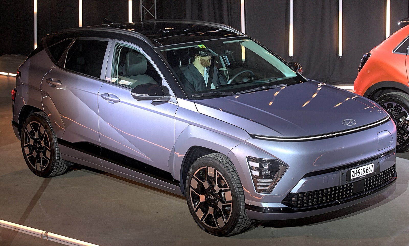 Hyundai Kona eléctrico en un salón del automóvil, iluminado de tres cuartos delantero