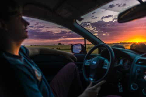 Interior de un coche desde el asiento del conductor, circulando por carretera al atardecer