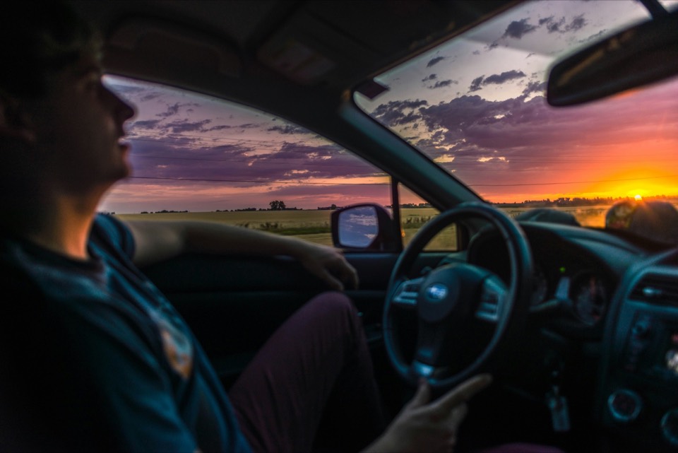 Interior de un coche desde el asiento del conductor, circulando por carretera al atardecer
