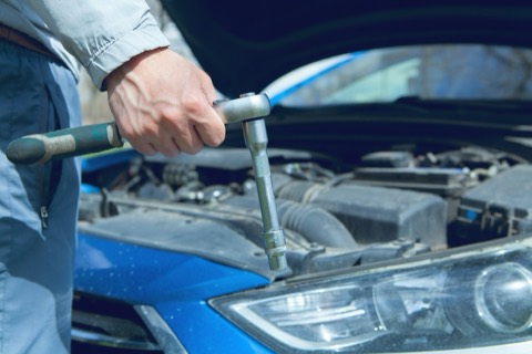 Manos apretando una pieza del motor con una llave de carraca