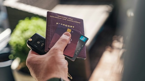 Mano sosteniendo un documento de viaje junto a otros documentos