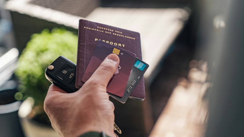 Mano sosteniendo un documento de viaje junto a otros documentos