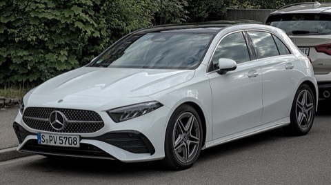 Mercedes Clase A W177 blanco de tres cuartos delantero aparcado junto a un seto, con luz de día