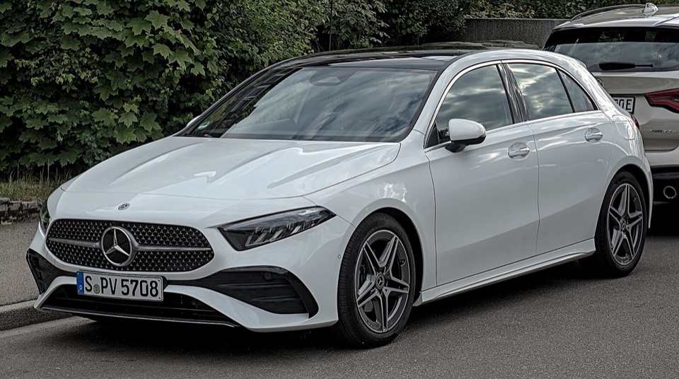 Mercedes Clase A W177 blanco de tres cuartos delantero aparcado junto a un seto, con luz de día