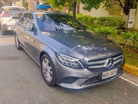 Mercedes Clase C W205 gris aparcado en una calle urbana con vegetación al fondo