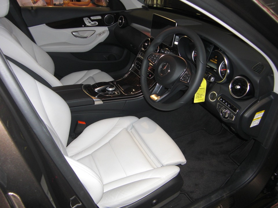 Interior de un Mercedes Clase C W205 con tapicería clara, volante y consola de madera