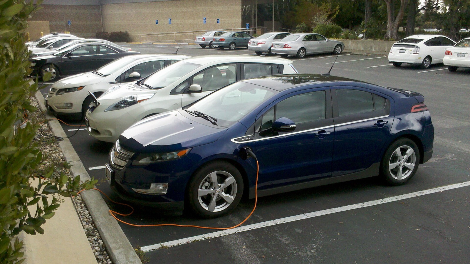 Un Nissan Leaf y un Chevrolet Volt cargando en un punto de recarga público