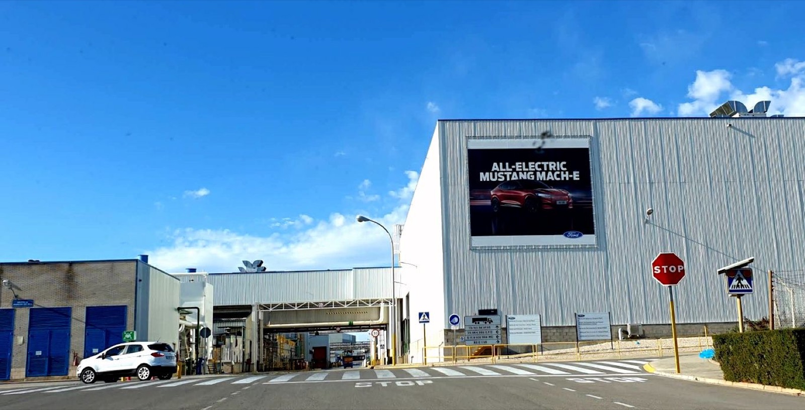 Acceso a la planta de Ford en Almussafes, con un cartel del Mustang Mach-E eléctrico