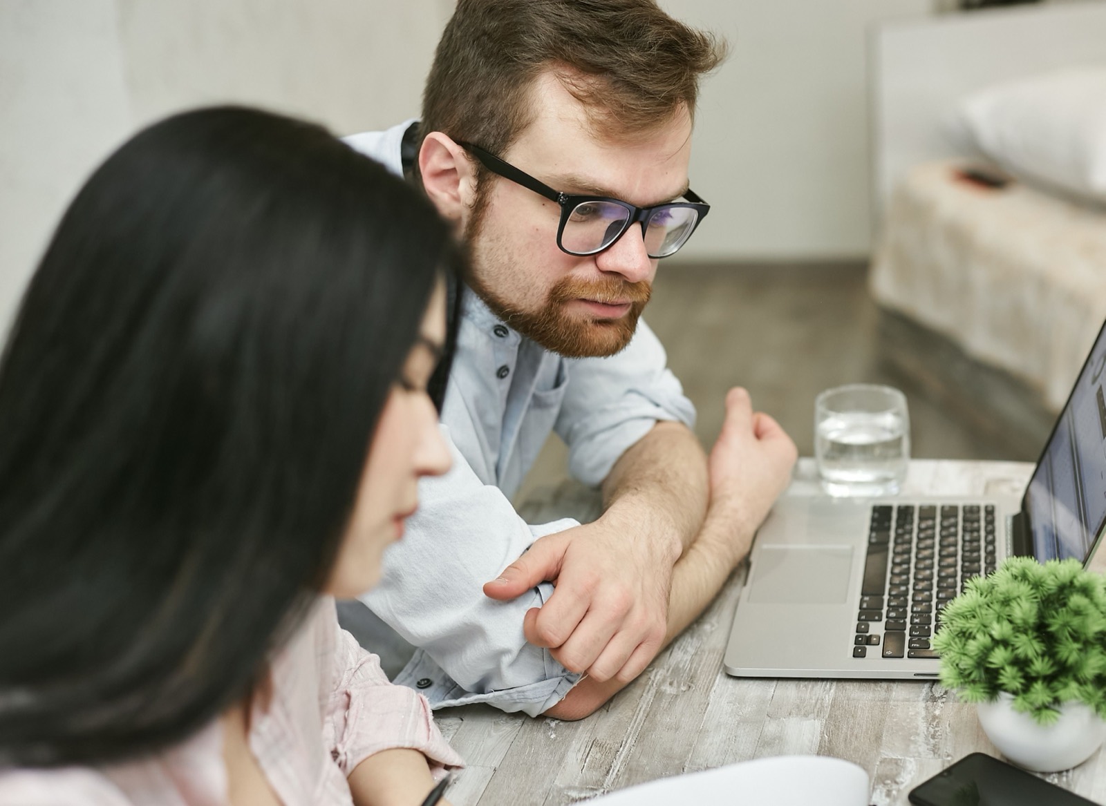 Dos personas revisando información en un ordenador portátil sentadas a una mesa