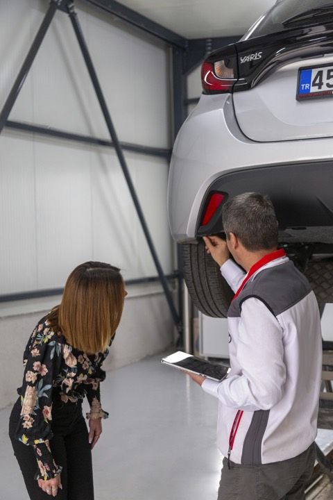 Dos personas revisando los bajos de un coche antes de comprarlo