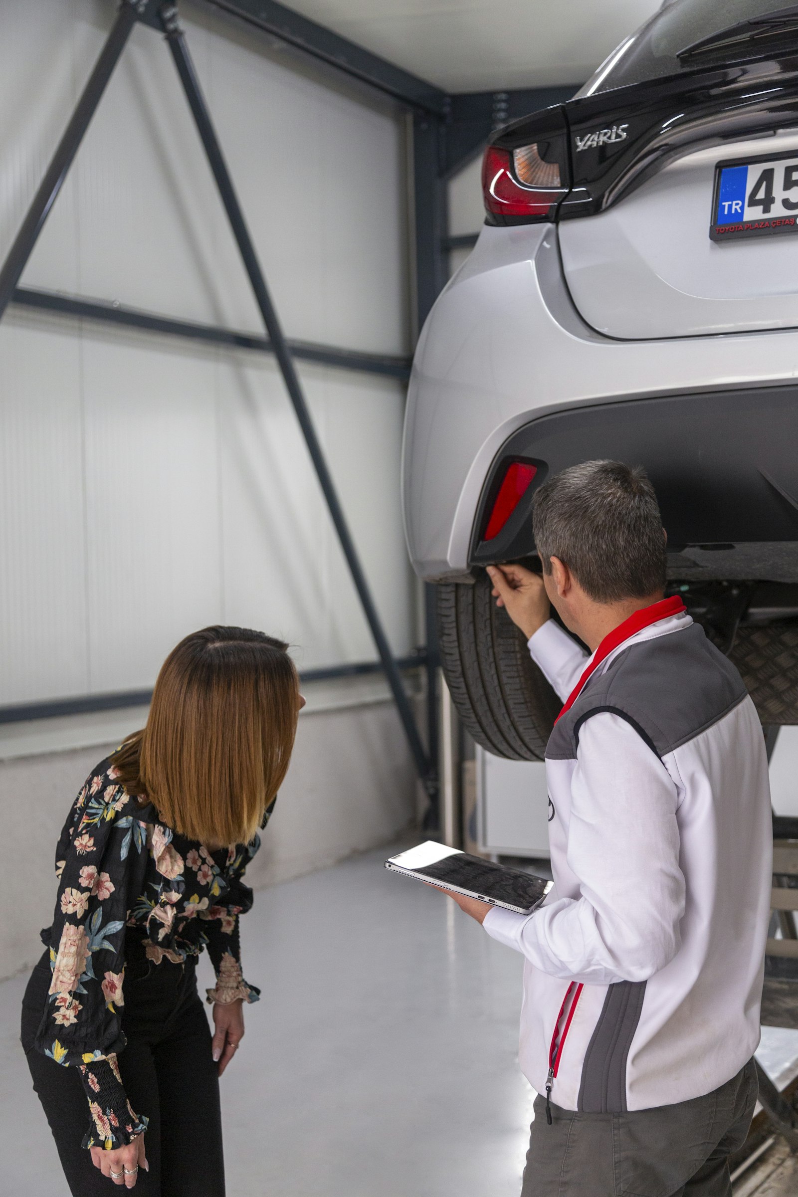 Dos personas revisando los bajos de un coche antes de comprarlo