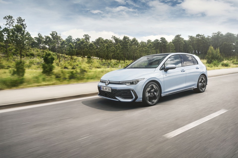 Volkswagen Golf blanco de tres cuartos delantero circulando por una carretera entre pinos