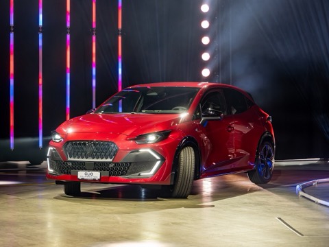 Renault Clio VI rojo full hybrid E-Tech de tres cuartos delantero sobre una plataforma de salón del automóvil