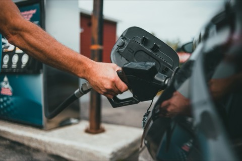 Mano sosteniendo la manguera del surtidor mientras reposta en una gasolinera