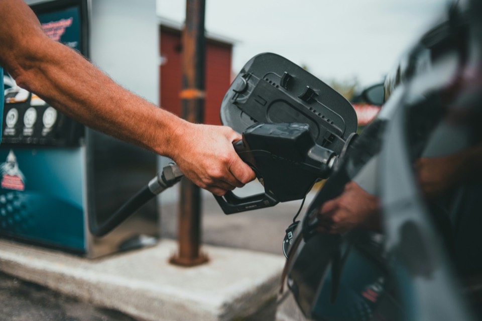 Mano sosteniendo la manguera del surtidor mientras reposta en una gasolinera