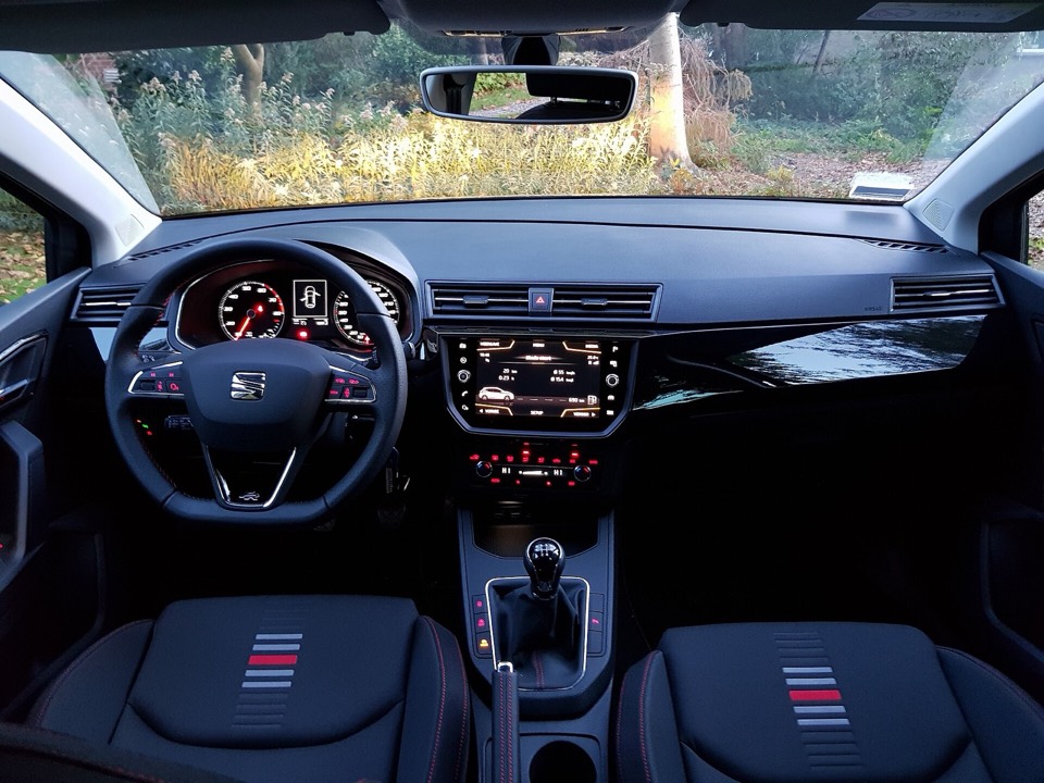 Salpicadero de un SEAT Ibiza 6F con cuadro analógico, pantalla central elevada y asientos con costuras rojas