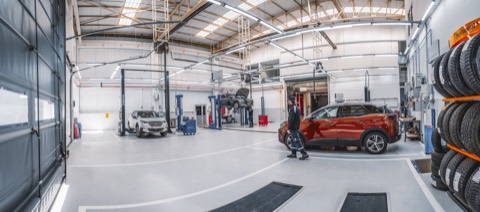 Nave de un taller oficial con varios coches sobre elevadores y luz natural