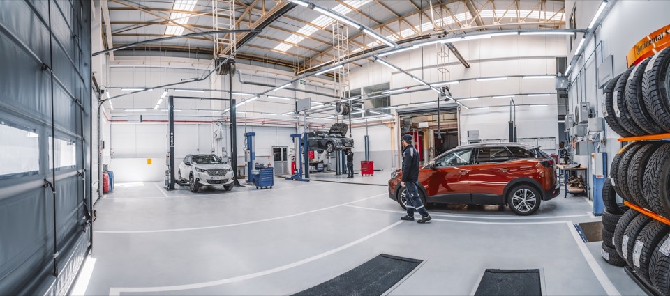 Nave de un taller oficial con varios coches sobre elevadores y luz natural