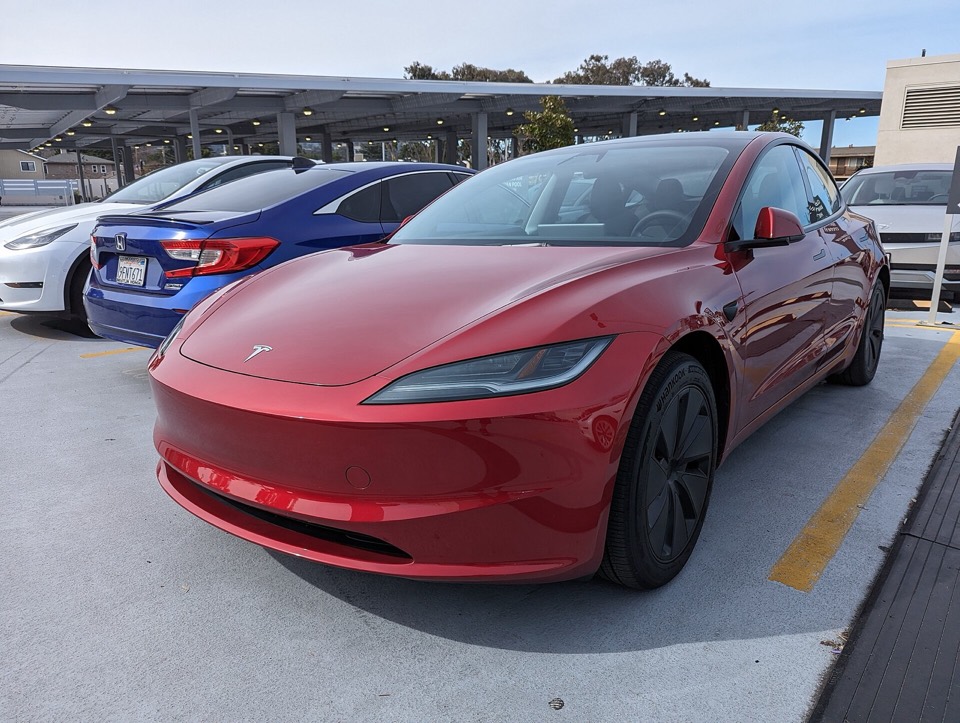 Tesla Model 3 actualizado, rojo, de tres cuartos delantero en un aparcamiento